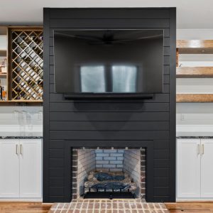Custom wall unit with wine storage, glass cabinetry, and floating wood shelves flanking a fireplace and mounted TV