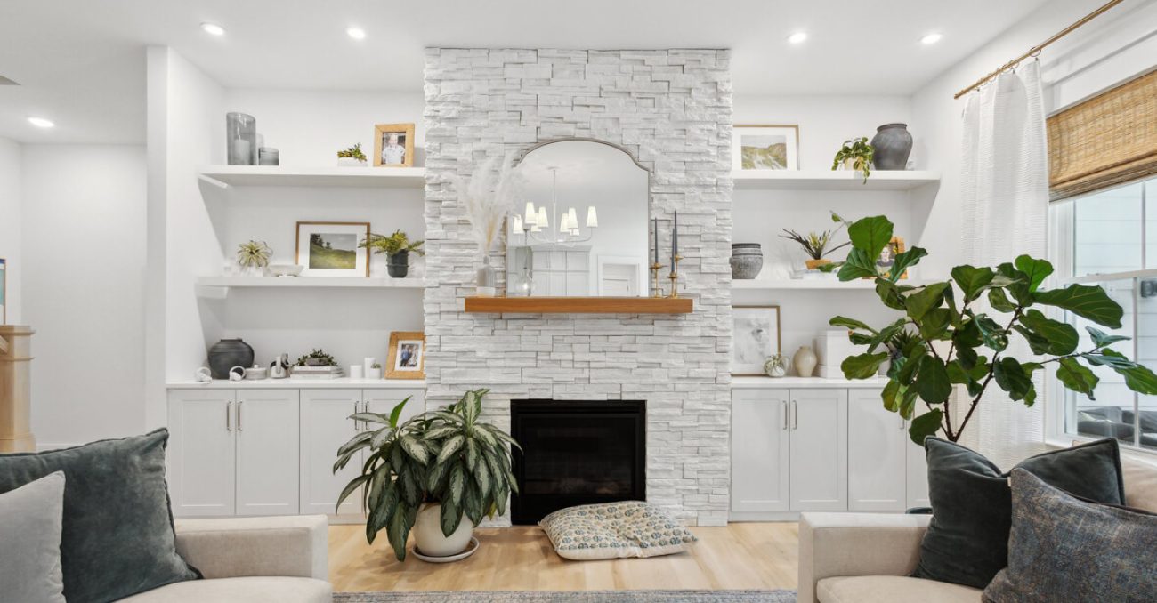Symmetrical white wall unit with floating shelves and cabinetry flanking a stacked stone fireplace