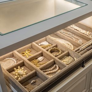 Tan velvet jewelry tray on pull-out shelf, counter with glass cutout