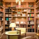 Built-in shelving featuring built-in window seat and work desk, slanted book display shelf, and a rolling ladder for added accessibility.