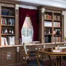 Traditional library built-ins with ornate trim and crown molding, carved corbels, and inset panel doors.