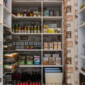 Walk-in pantry with corner shelving and pull-out trash cans.