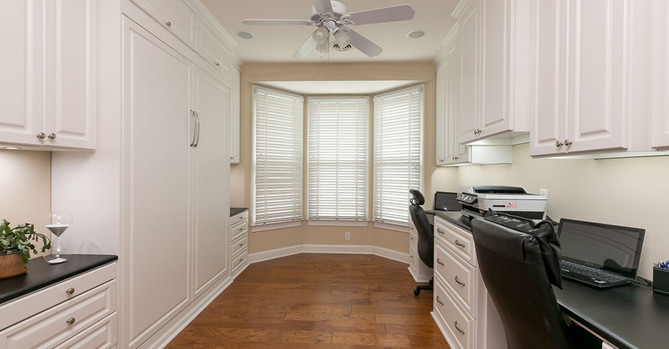 Home office with built-in wall bed to transform space into guest room. Dual work stations built in with raised panel cabinet doors.