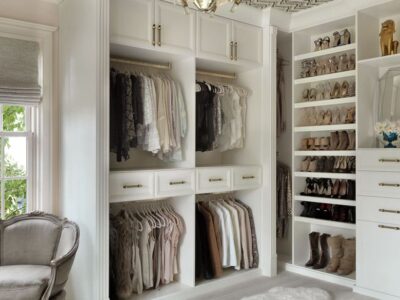 Bright custom walk-in closet with white cabinetry, hanging storage, and built-in shoe shelves.