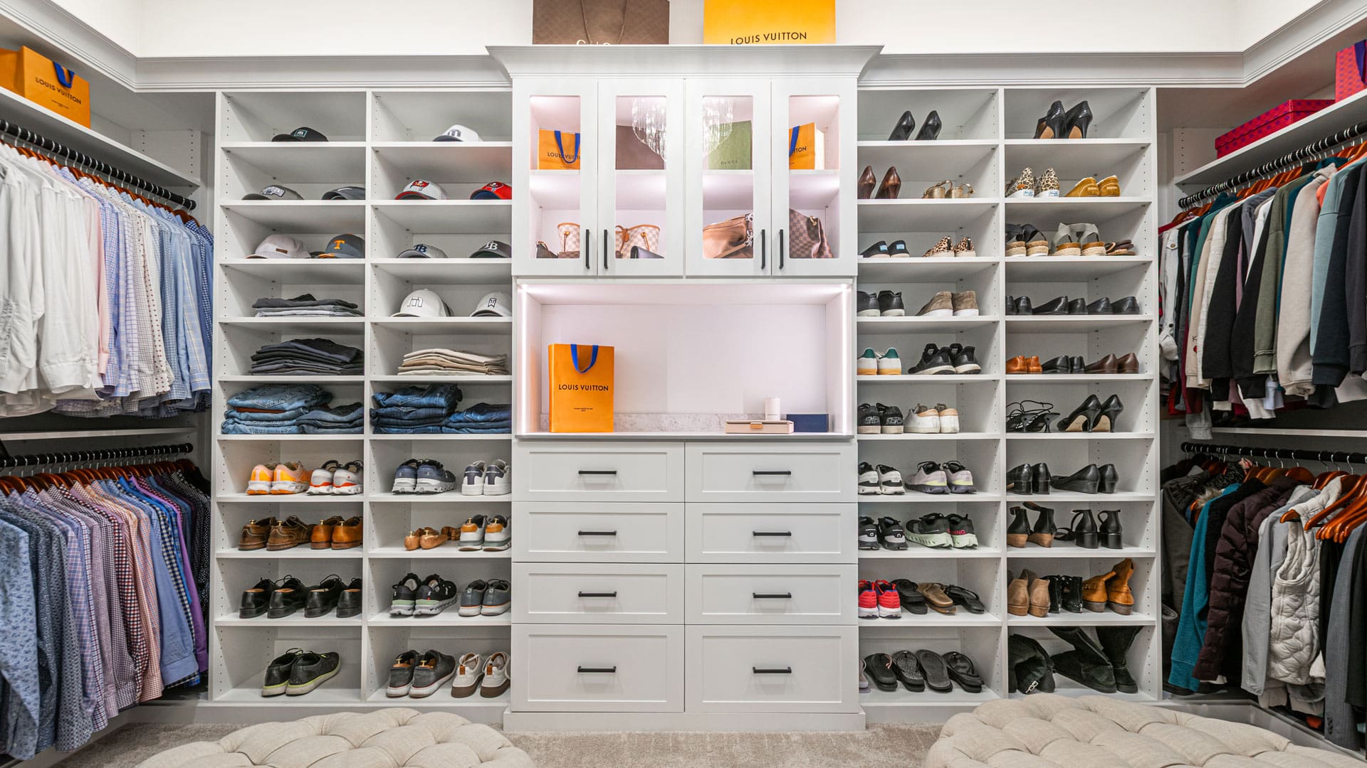 Custom walk-in closet with shoe shelving, hanging storage, and a central drawer system.